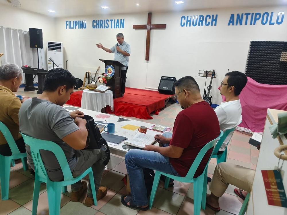 A pastor teaching at a podium while students take notes