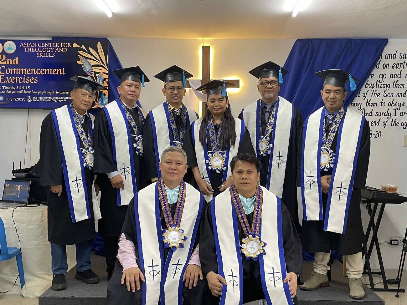 A.C.T.S. pastors and professors in graduation regalia standing before a wooden cross